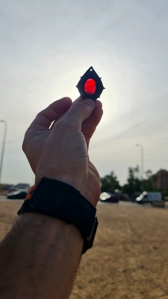 Sol de Ébano sostenido a contraluz, amuleto de ébano con piedra iluminada por el sol